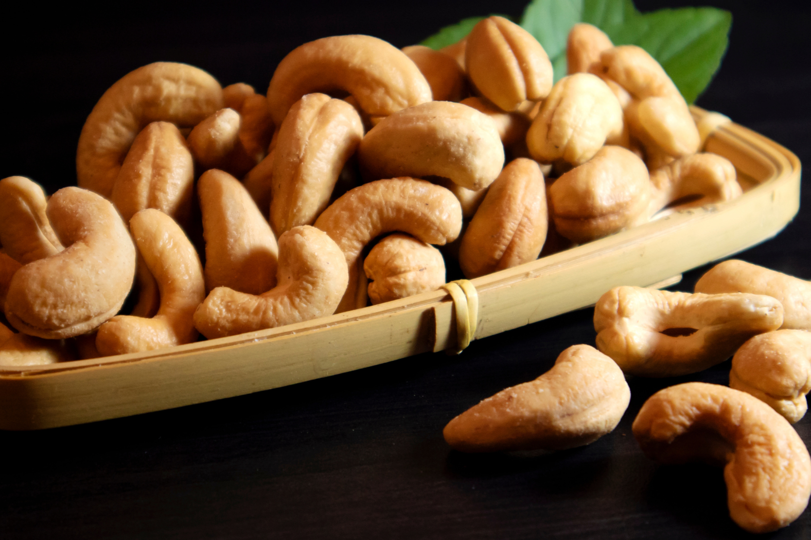 Cashews on a wooden tray with a dark background